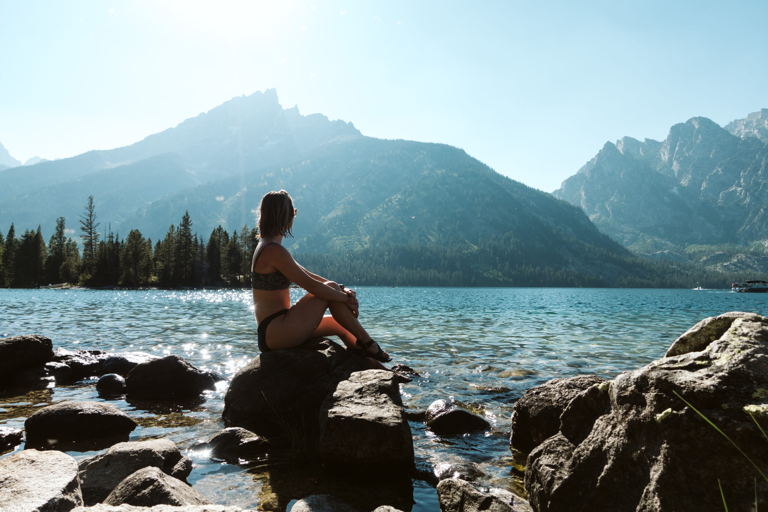 Woman sits on rock at Jenny Lake in Grand Teton National Park.